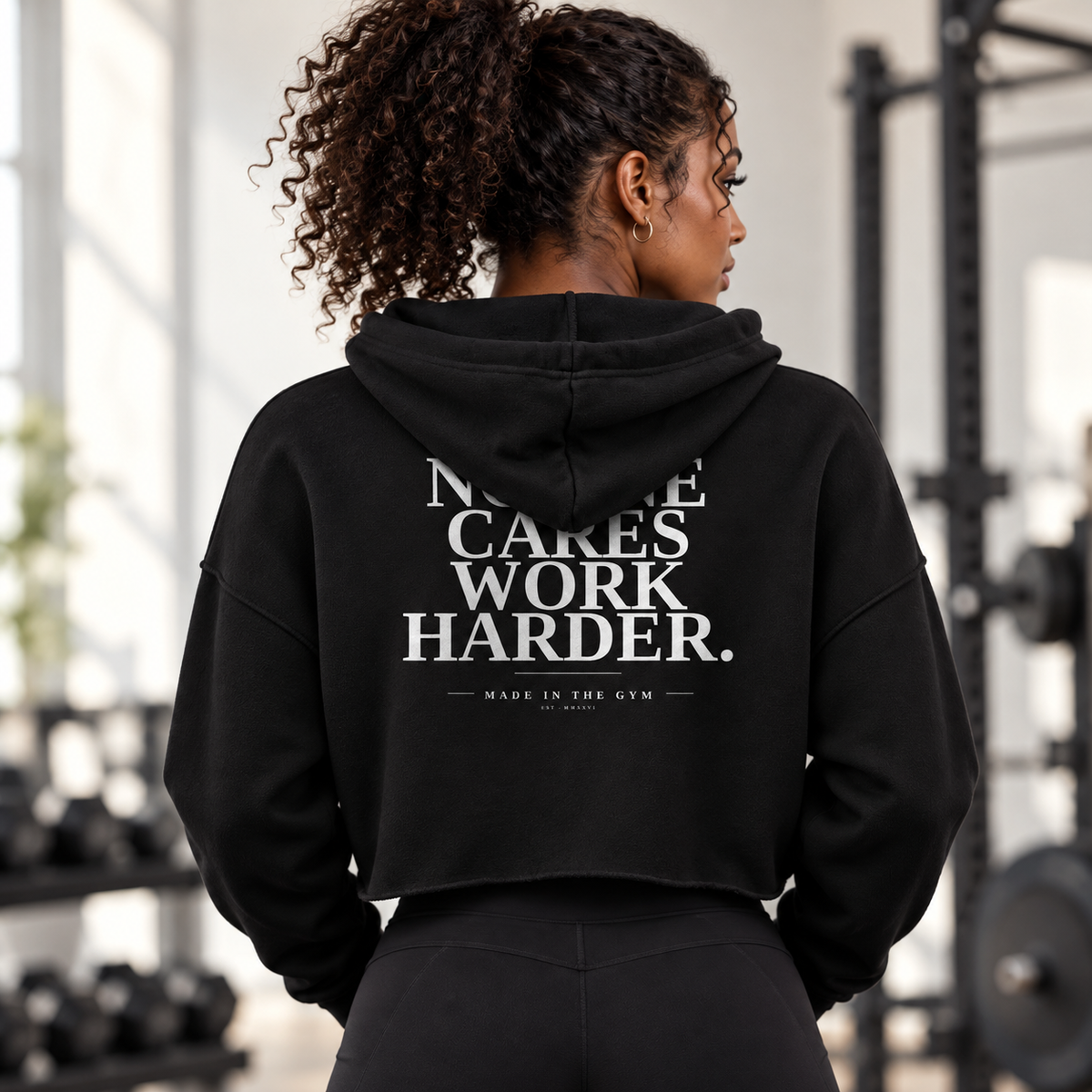 Adult woman athlete wearing the black MITG No One Cares cropped hoodie, back view showing the slogan artwork